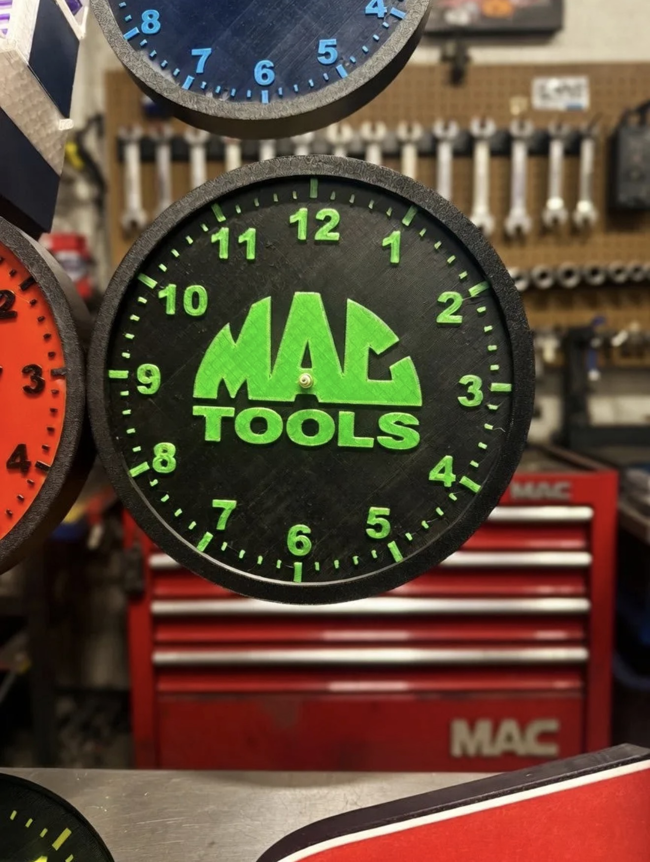 Custom black and green 3D printed tool-brand-style clock face hanging in a workshop.