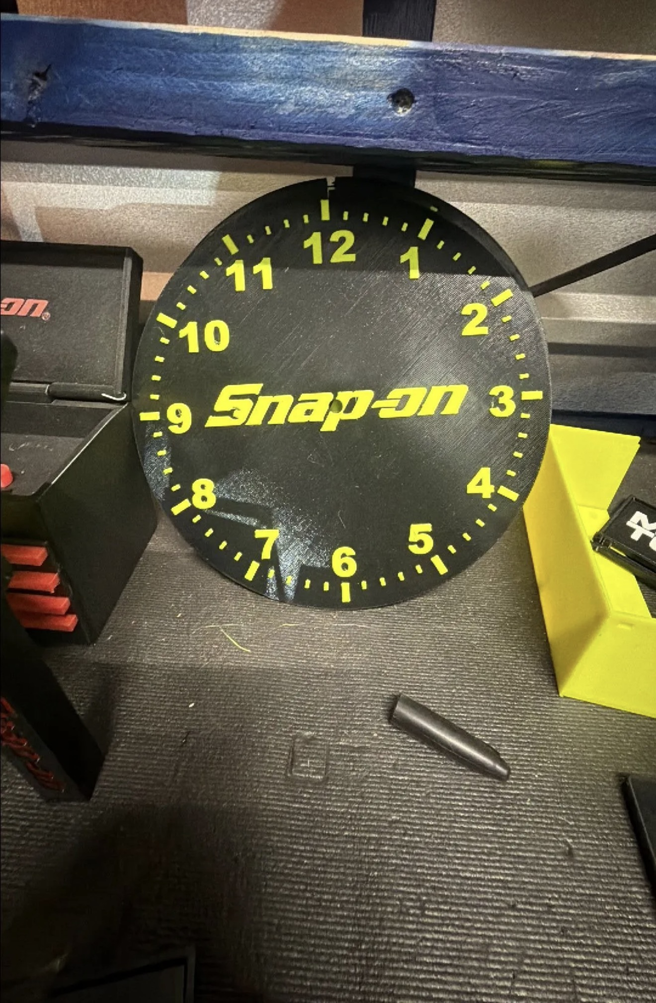 Custom black and yellow 3D printed tool-brand-style clock face on a workbench.
