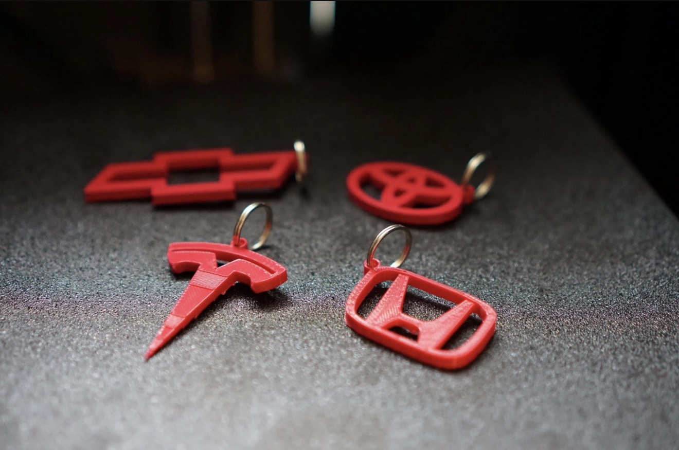 Custom red 3D printed automotive-style keychains with metal key rings.