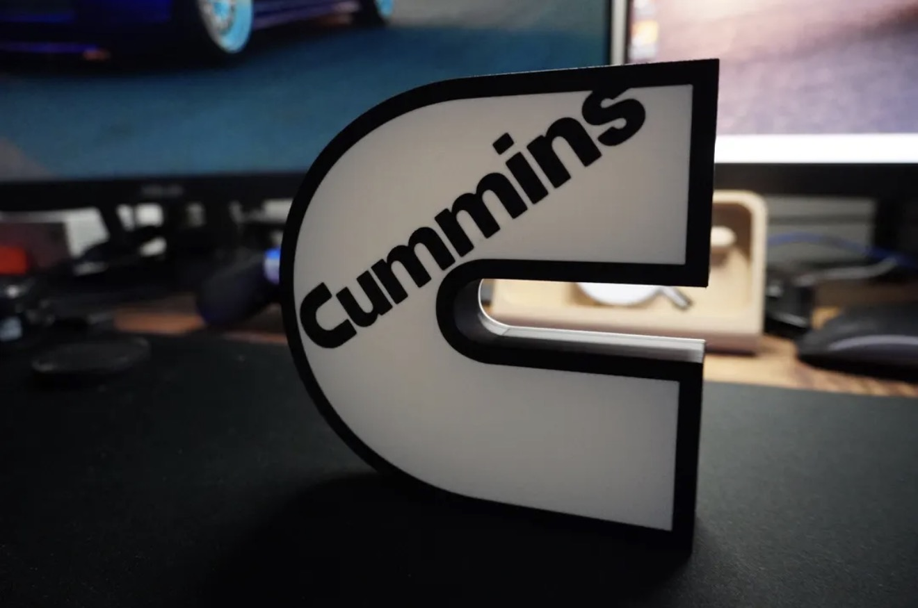 Custom white and black illuminated wordmark-style logo lightbox sign on a desk.